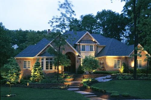 A house at dusk with the front walk and the plantings along it lit.