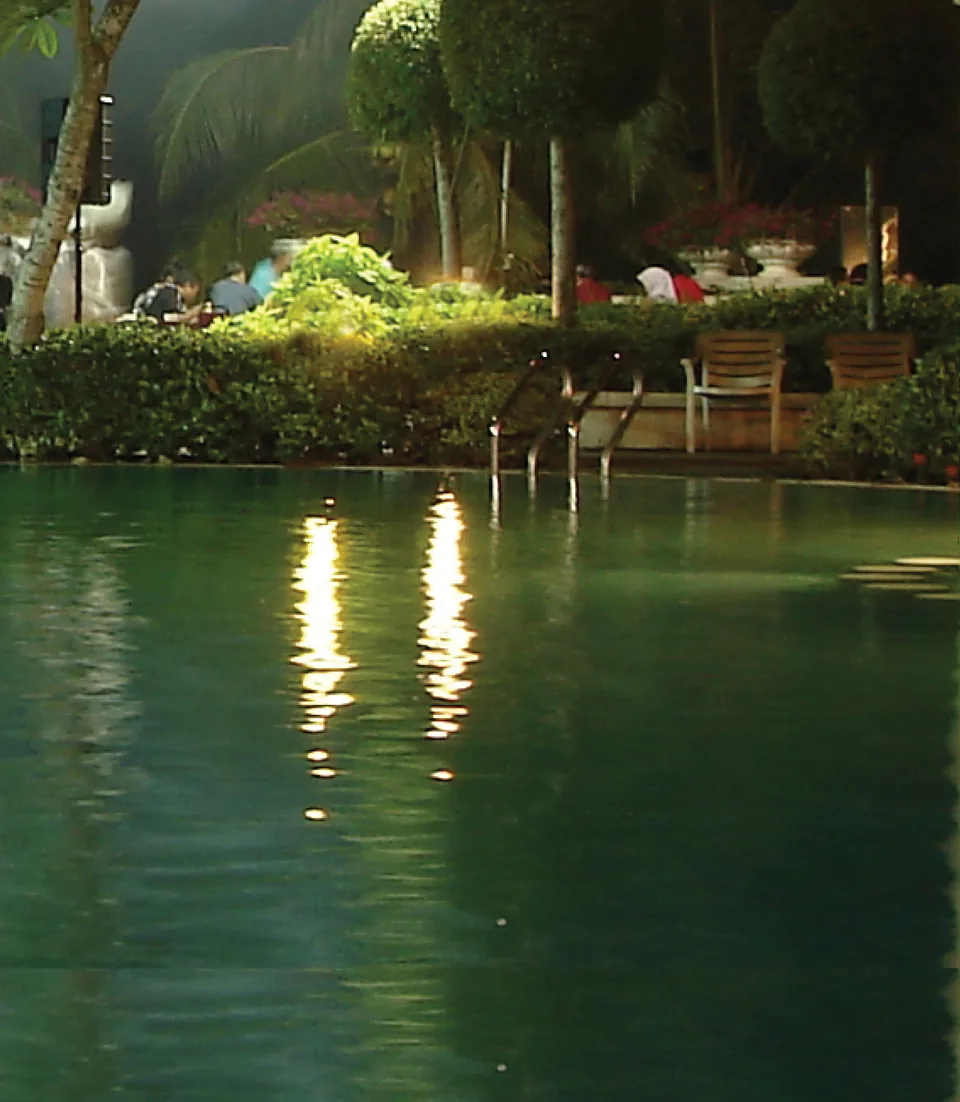 Two columns of warm lamplight reflected across the surface of a pool at night.
